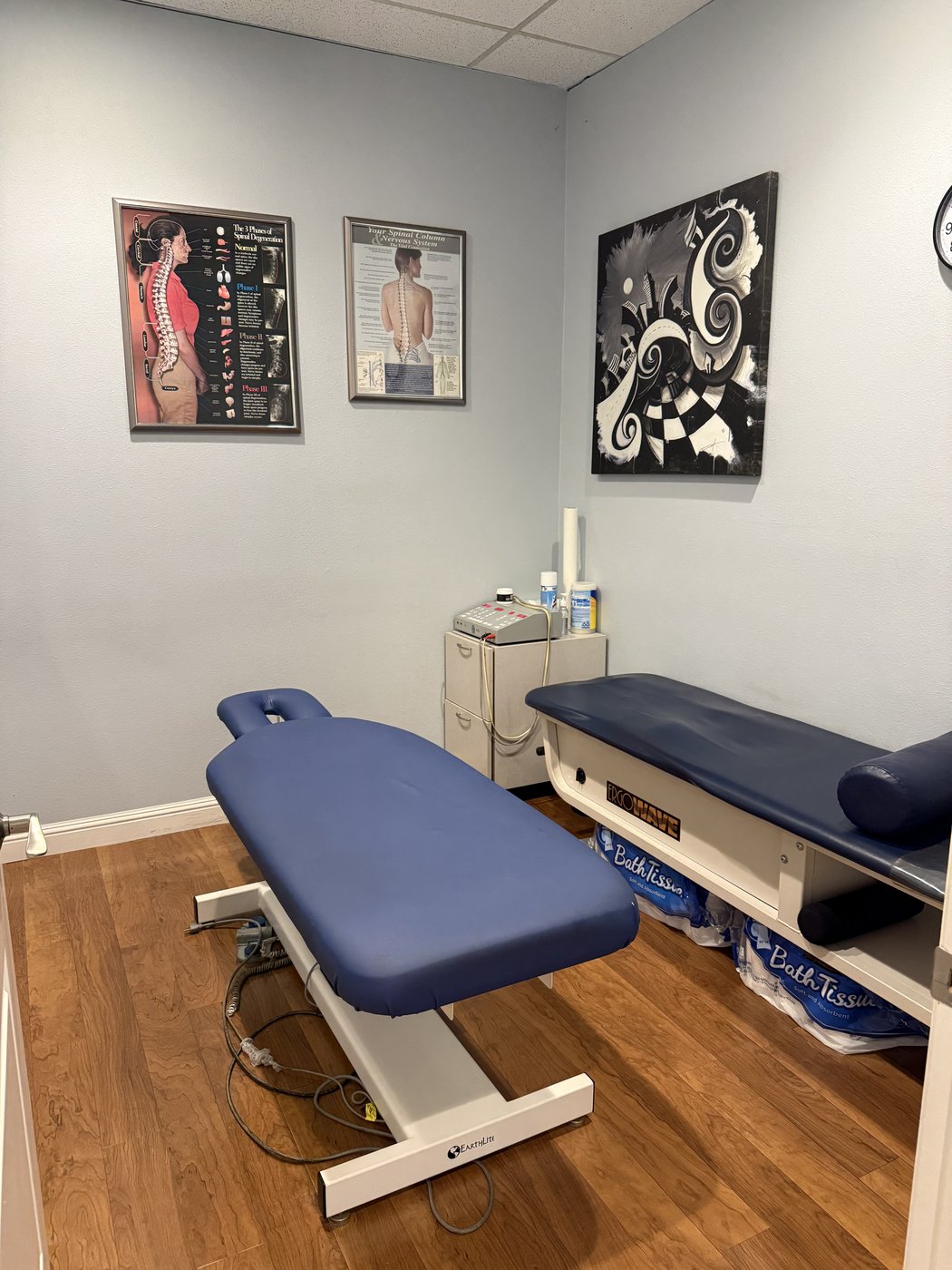 VAL Chiropractic second treatment room with electric adjusting table and spinal anatomy charts